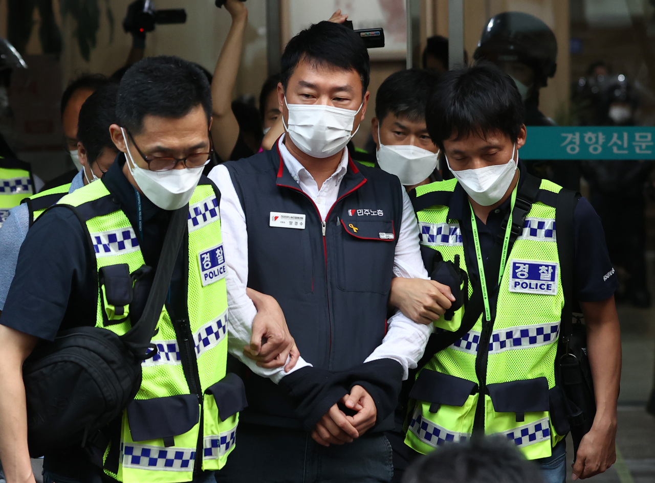 Yang Kyung-soo, head of the Korean Confederation of Trade Unions, is escorted to a police vehicle while wearing handcuffss as police executed an arrest warrant for him Thursday morning. (Yonhap)