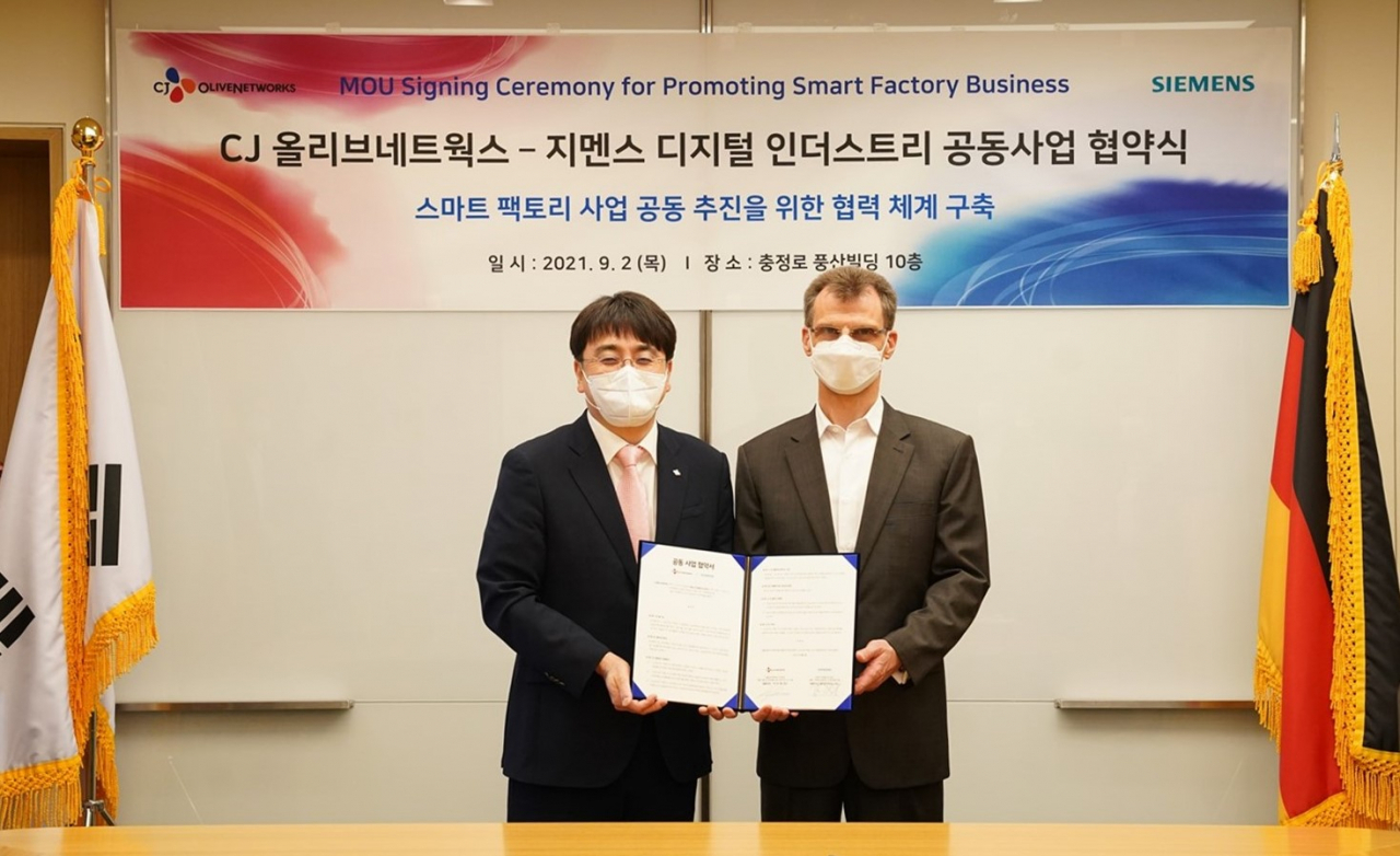 한국지멘스 본사에서 열린 업무협약식에서 차인혁(왼쪽) CJ올리브네트웍스 대표와 토마스 슈미드 한국지멘스 디지털 인더스트리 부문 대표가 기념 사진을 촬영하고 있다. [CJ올리브네트웍스 제공]