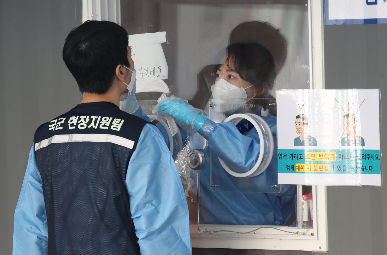 신종 코로나바이러스 감염증(코로나19) 신규 확진자 수가 1천804명을 기록해 두 달째 네 자릿수를 기록한 4일 오전 서울 중구 서울역 광장에 설치된 코로나19 임시 선별검사소에서 의료진이 국군 현장지원팀 관계자의 검체를 채취하고 있다.[연합]