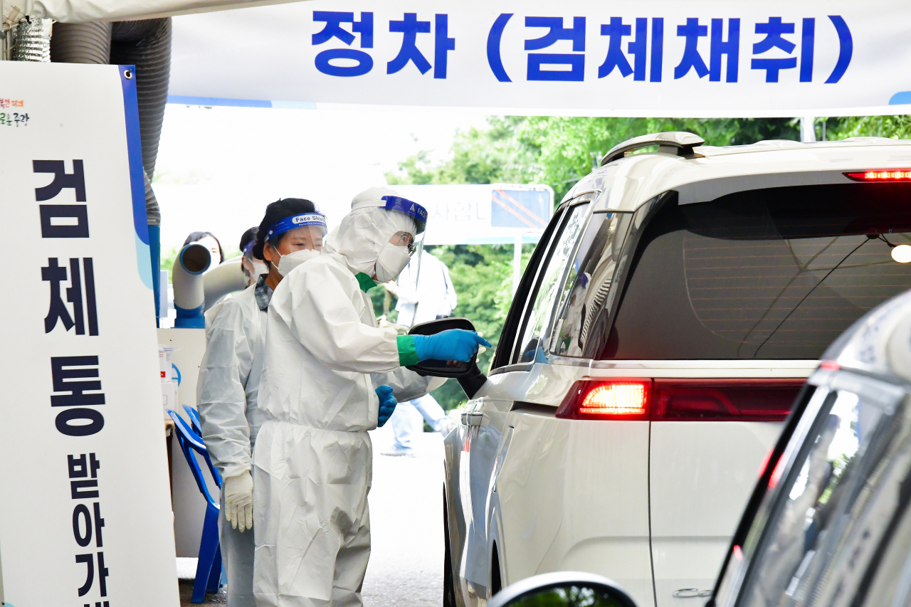 10일 오전 서울 망우저류조공원 드라이브스루 임시선별검사소 일일 진행요원으로 나선 류경기 중랑구청장이 코로나19 검사를 위해 대기하는 시민에게 검체통을 전달하고 있다. [중랑구 제공]