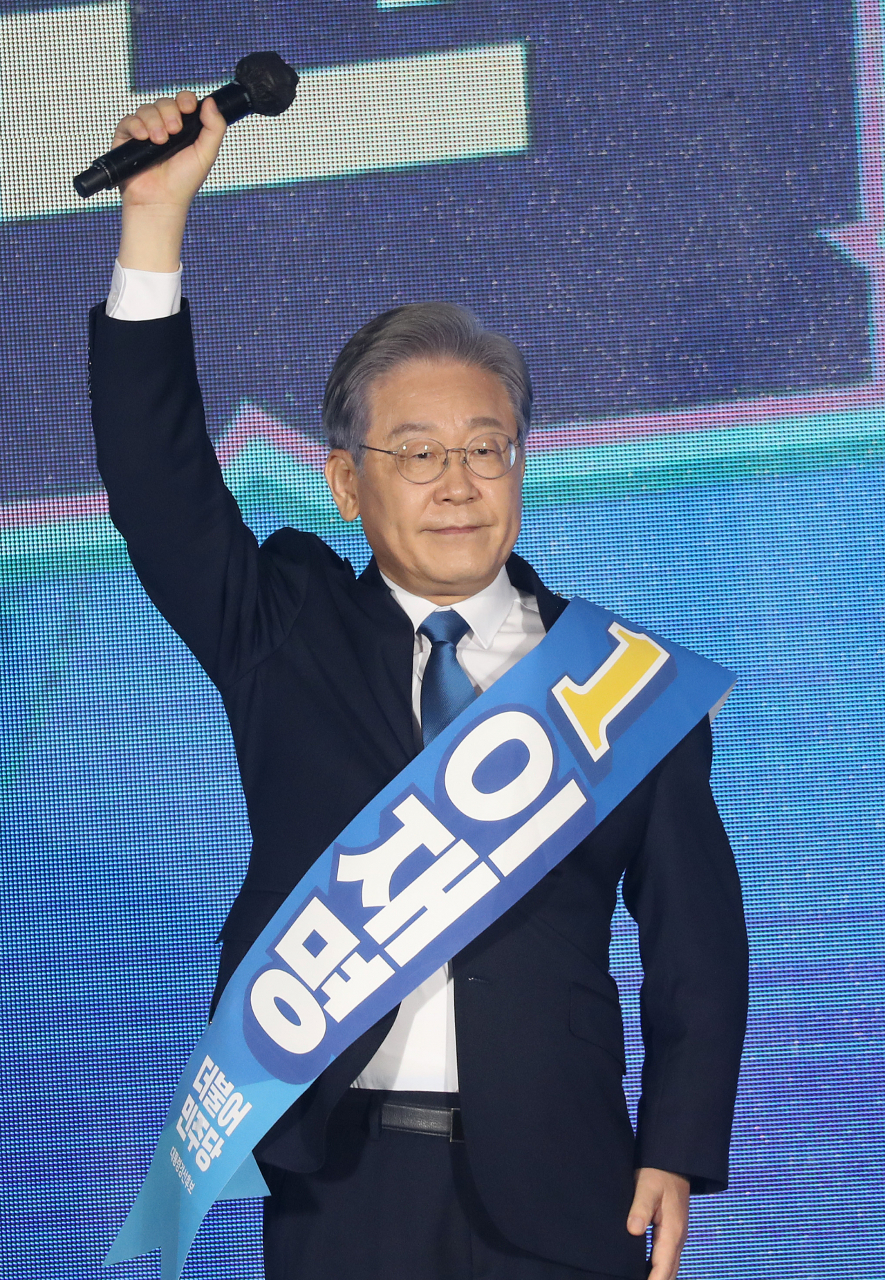 12일 오후 강원 원주시 오크밸리리조트 컨벤션센터에서 열린 더불어민주당 강원권역 순회경선 합동연설회에서 이재명 후보가 정견 발표를 마친 뒤 마이크를 든 손을 높이 들고 있다. [연합]
