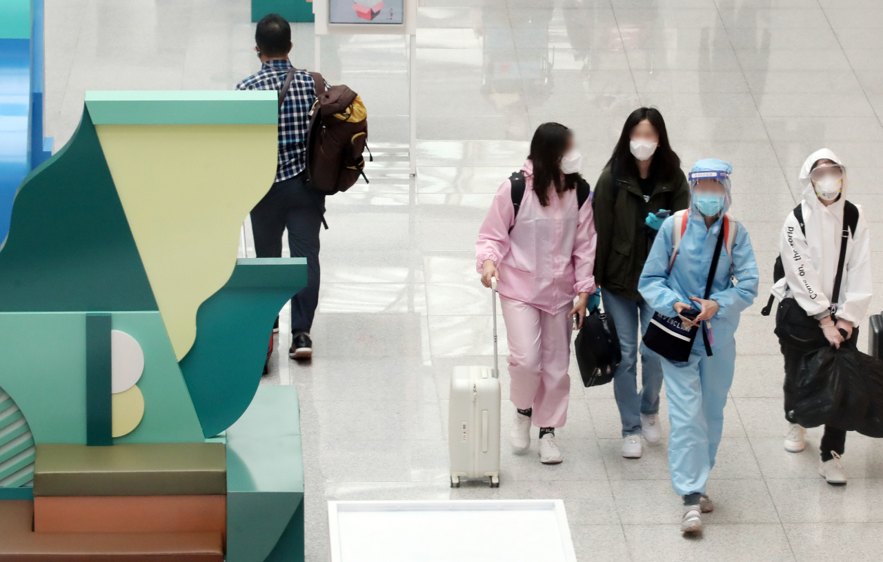 지난 8월 20일 오후 영종도 인천국제공항 제1여객터미널 출국장 보세구역에서 방역복과 고글로 중무장한 해외 출국자가 면세점 앞을 지나고 있다. [연합]