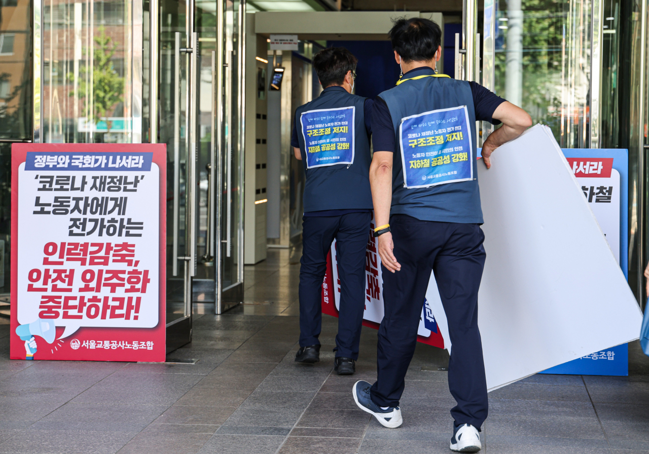 13일 서울 성동구 서울교통공사 사옥에 노조 관계자가 노조의 주장이 담긴 팻말을 설치한 뒤 교섭장으로 향하고 있다.[연합]