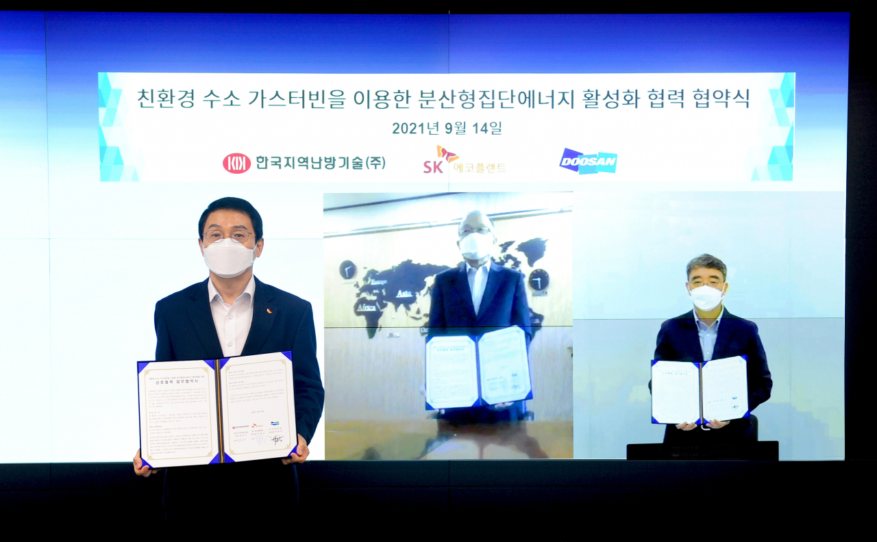 사진은 주양규 SK에코플랜트 플랜트사업단장(왼쪽 첫번째)과 김호기 한국지역난방기술 전무(왼쪽 두번째), 박홍욱 두산중공업 부사장이 온라인 화상 협약식을 마친 후 협약서를 들고 기념촬영을 하는 모습.[SK에코플랜트 제공]