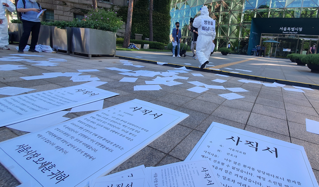 민주노총 의료연대본부가 15일 서울시청 앞에서 코로나19 간호인력 기준 발표 촉구 기자회견 후 사직서를 뿌리는 항의행위를 하고 있다. [연합]