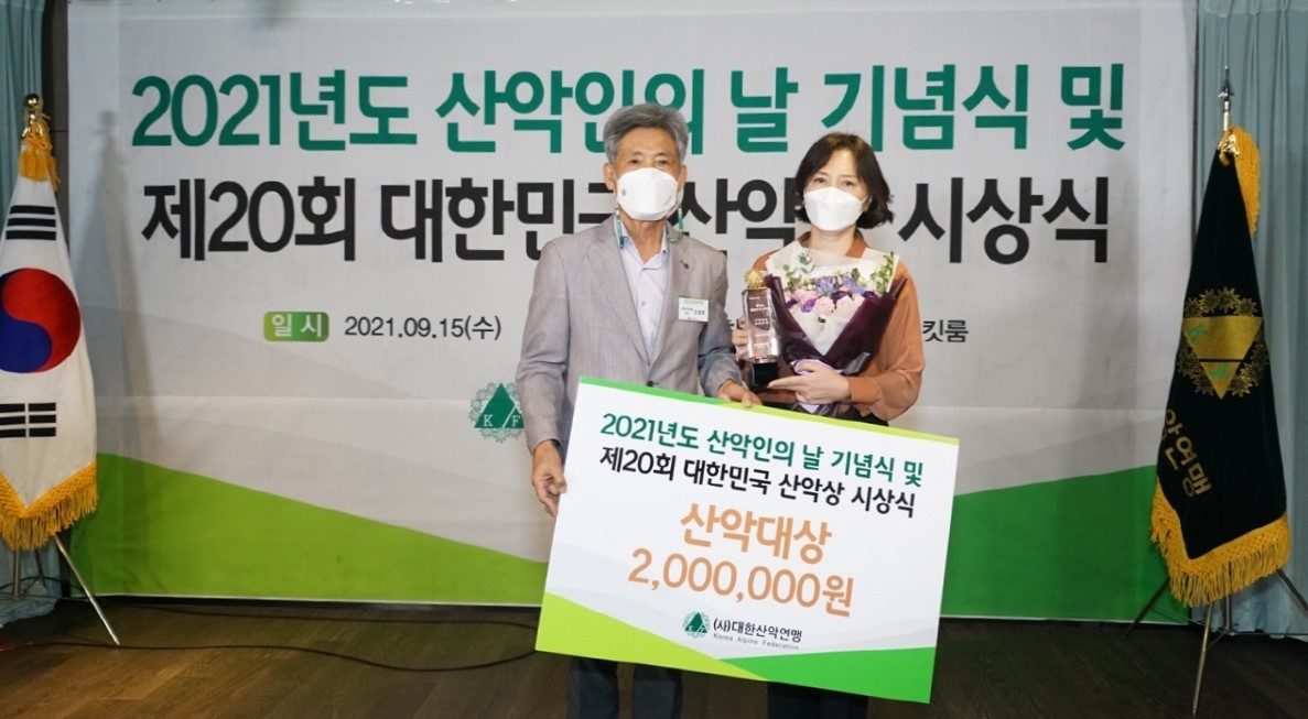 고 김홍빈 대장의 부인이 대리 수상하고 기념촬영하고 있다. [산악연맹 제공]