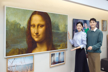 경기 수원시에 위치한 삼성 프리미엄 스토어 갤러리아 광교점에서 삼성전자 모델이 85형 더 프레임을 통해 레오나르도 다 빈치 의 ‘모나리자’ 등 루브르 대표 작품을 소개하고 있다. [삼성전자 제공]