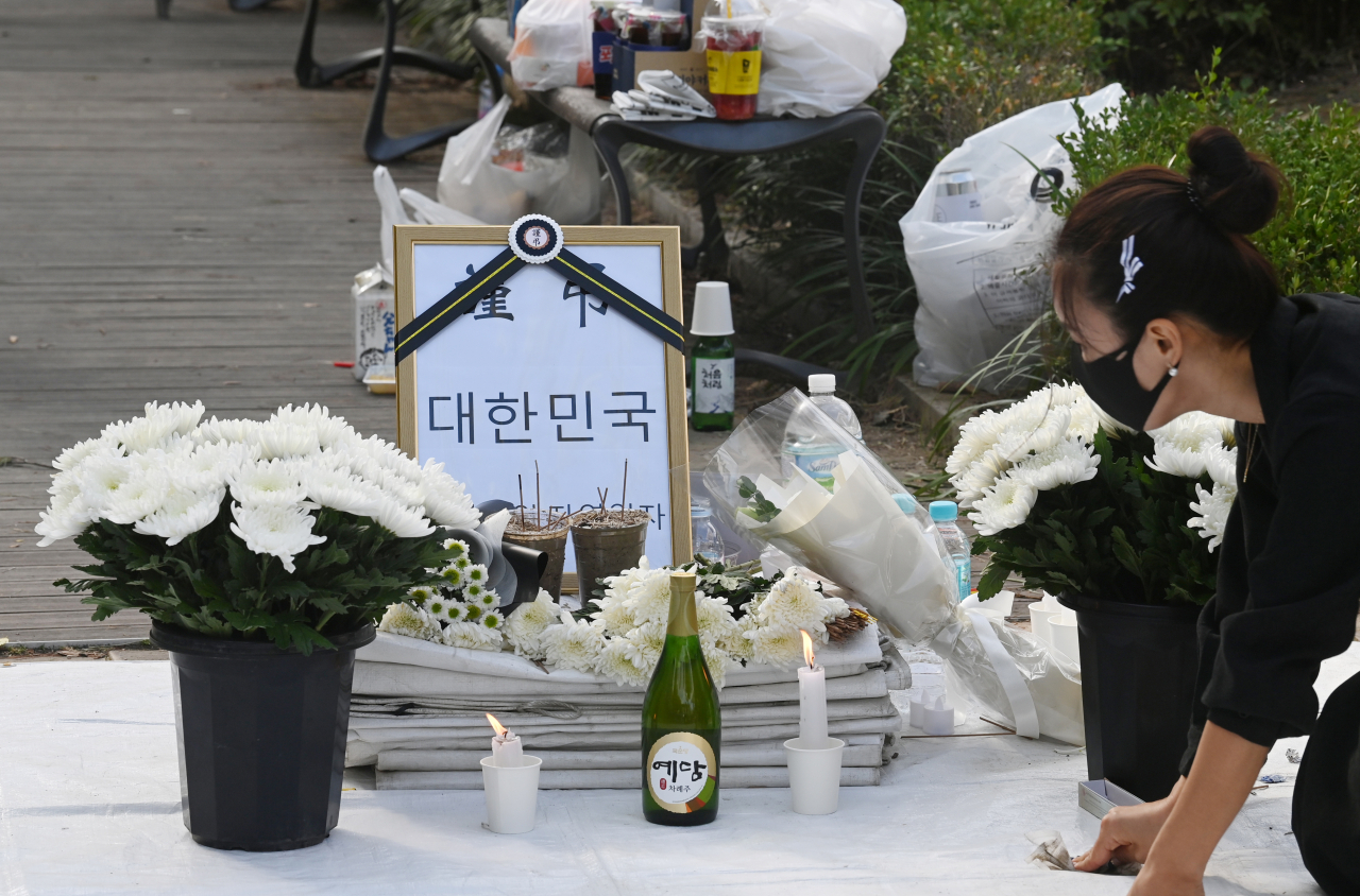 17일 서울 여의도 국회의사당역 앞에 마련된 자영업자 임시 합동분향소에서 관계자가 국화꽃 등 물품을 정돈하고 있다. [연합]