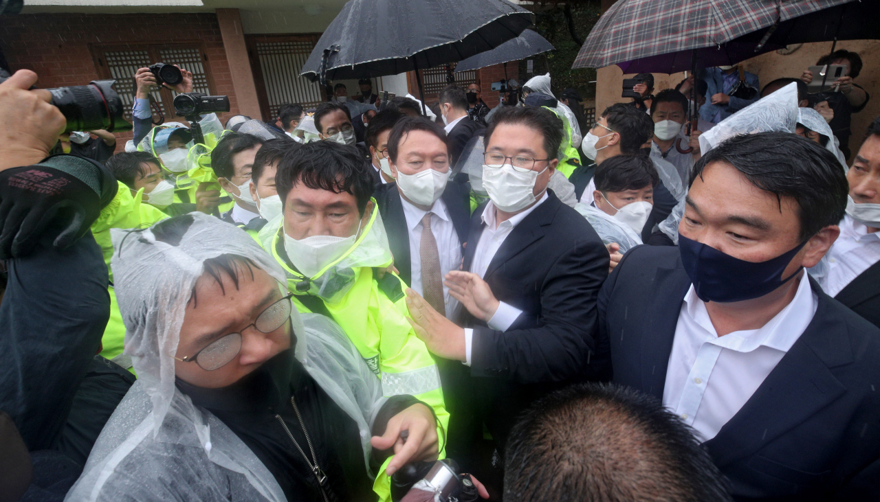 국민의힘 대권주자인 윤석열 전 검찰총장이 17일 경북 구미시 상모동에 있는 박정희 전 대통령의 생가를 찾았다가 헌화 및 추모 후 보수단체 회원들의 반대로 실랑이를 벌이는 과정에서 비에 젖어 떠나고 있다. [연합]