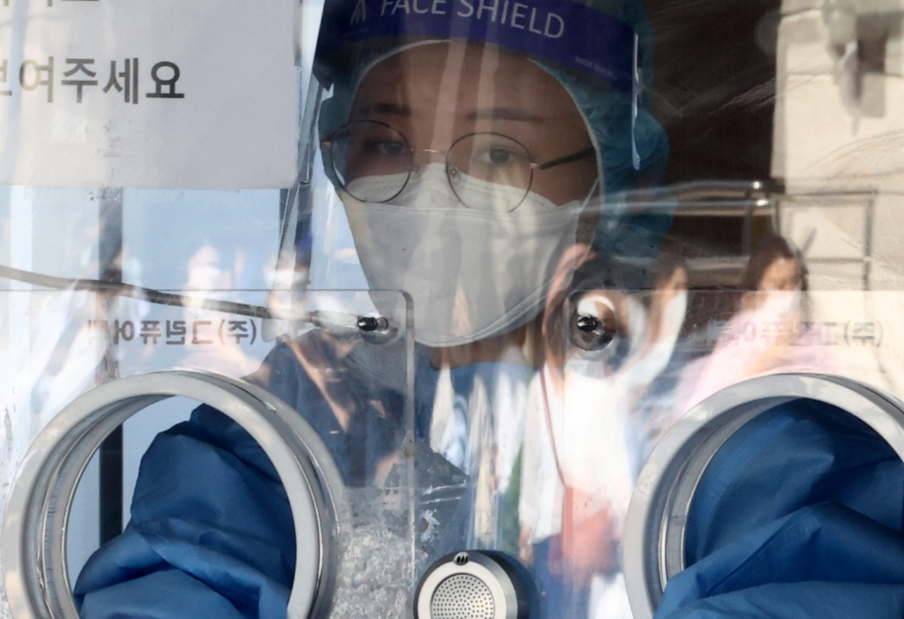 신종 코로나바이러스 감염증(코로나19) 신규 확진자 수가 1605명을 기록한 20일 오전 서울역 코로나19 선별진료소에서 의료진이 진료소 앞을 지나는 귀성객들을 바라보고 있다. [연합]