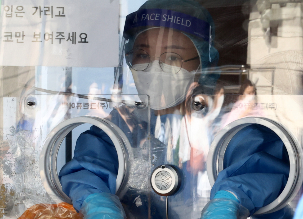 추석 연휴였던 이달 20일 오전 서울 중구 서울역 코로나19 선별진료소에서 의료진이 진료소 앞을 지나는 귀성객들을 바라보고 있다. [연합]