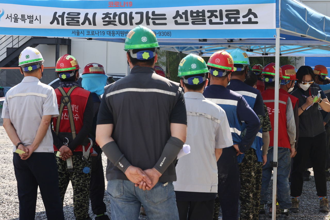 24일 오전 서울 강남구의 한 건설 현장에 마련된 '서울시 찾아가는 선별진료소'에서 작업자들이 코로나19 검사를 받기 위해 줄을 서 있다. [연합]
