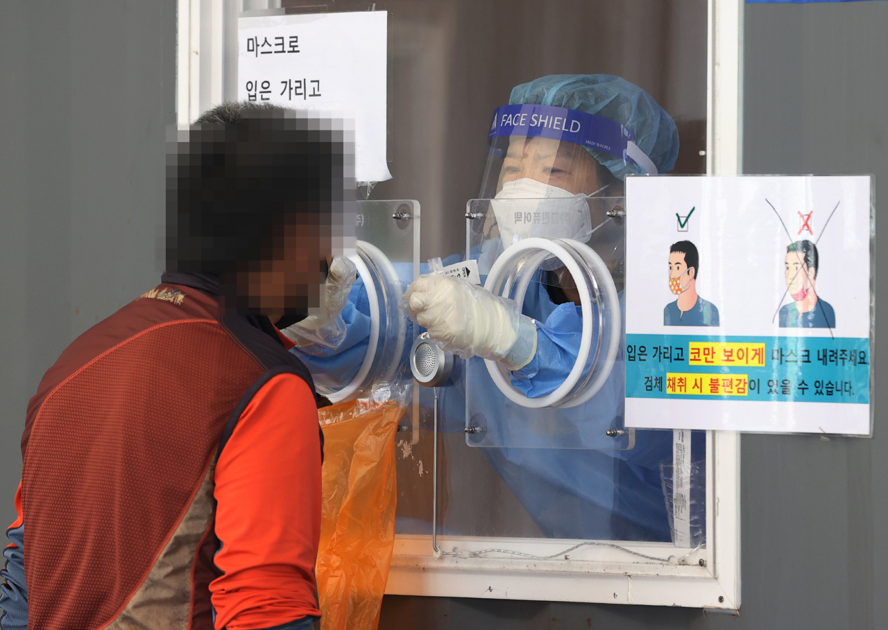 지난 25일 오전 서울역 광장에 마련된 중구임시선별검사소에서 의료진이 검체를 채취하고 있다. [연합뉴스 제공]