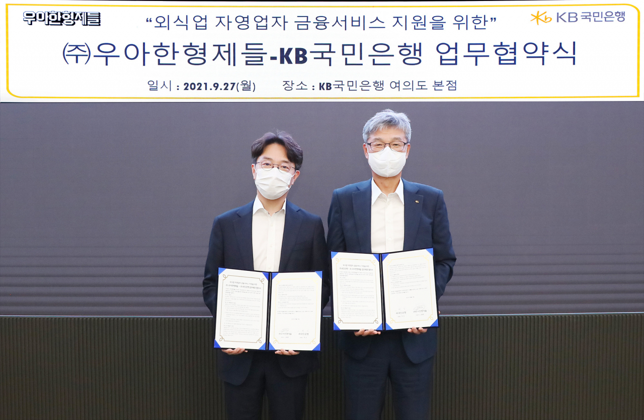 지난 27일 KB국민은행 여의도 본점에서 열린 외식업 자영업자 금융서비스 지원을 위한 KB국민은행-(주)우아한형제들 업무 협약식에서 허인(우측) KB국민은행장과 김범준 우아한형제들 대표이사가 업무협약을 체결하고 기념촬영을 하고 있다.