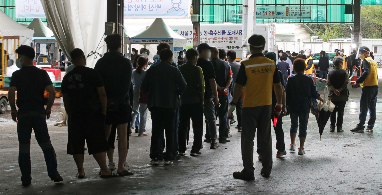 29일 오전 서울 송파구 가락농수산물도매시장에 설치된 찾아가는 선별검사소에서 상인과 시민들이 코로나19 검사를 받기 위해 대기하고 있다. [연합]