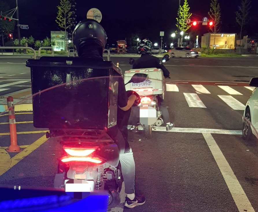 한 배달기사가 적색 신호등에서 정지선 뒤에 정차하고 있는 모습. [온라인 커뮤니티 캡처]