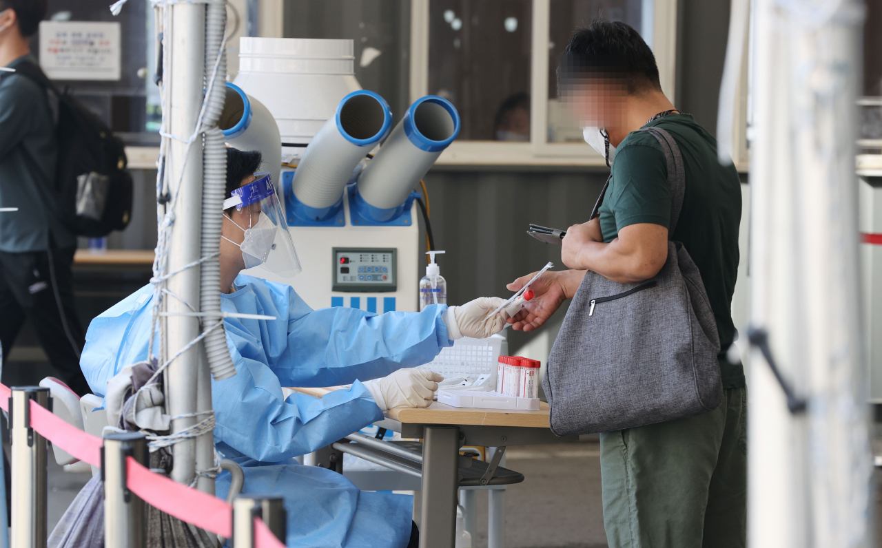 3일 서울역광장에 마련된 신종 코로나바이러스 감염증(코로나19) 임시 선별검사소에서 의료진이 검체 채취 키트를 건네고 있다. [연합]