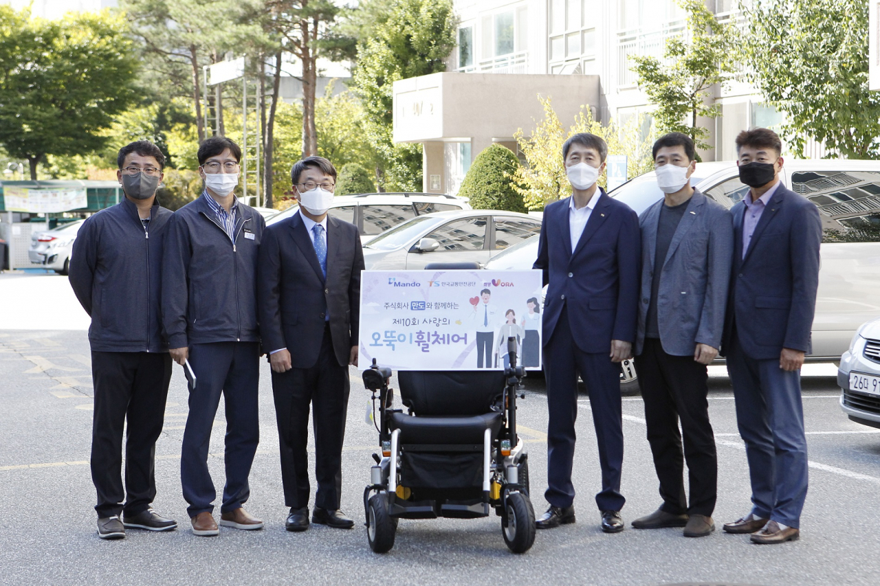 만도와 한국교통안전공단이 지난 30일 강원도 원주시에 거주하는 수혜자 자택을 방문해 ‘사랑의 오뚝이 휠체어’를 전달했다. 사진은 한국교통안전공단 이장규 강원본부장(오른쪽 세 번째)과 만도 홍영일 상무(왼쪽 세 번째)가 관계자들과 기념사진을 촬영하는 모습. [만도 제공]