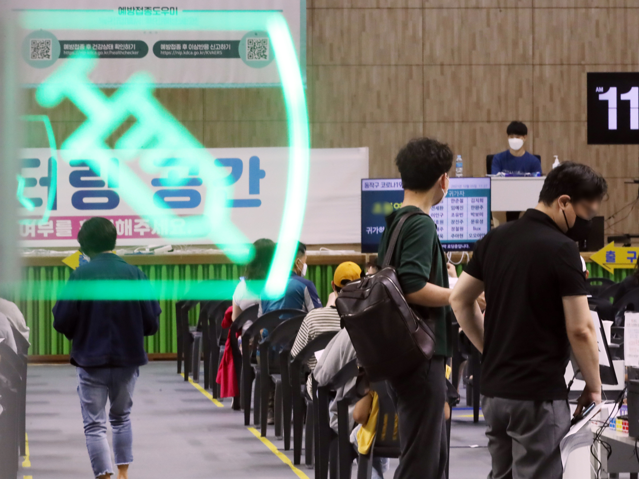 This photo taken Tuesday shows people waiting inside a COVID-19 vaccination clinic in Seoul. (Yonhap)