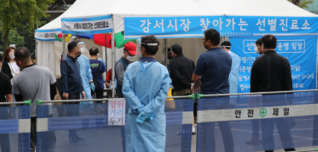 지난 6일까지 28명이 확진돼 코로나19 집단감염이 발생한 서울시 강서구 강서농산물도매시장 선별검사소에서 7일 오전 시장 관계자들이 검사를 받기 위해 줄을 서 있다. 연합뉴스