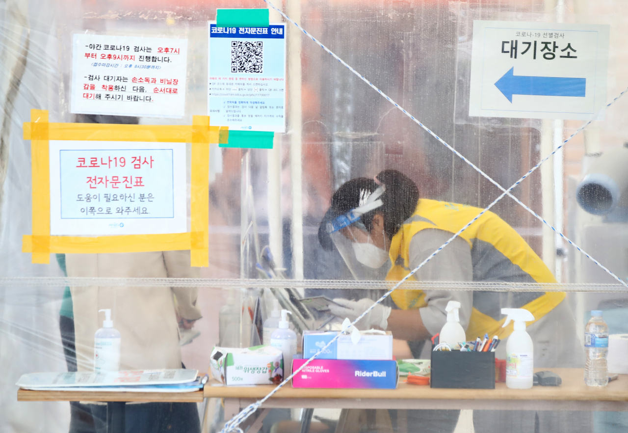 10일 0시 기준 신규확진자 수는 주말 검사 건수 감소 영향으로 1594명으로 집계됐다. 서울 마포농수산물시장 인근에 마련된 서울 마포구보건소 코로나19 선별진료소에서 한 관계자가 시민들이 작성한 문진표를 확인하고 있다. [연합]