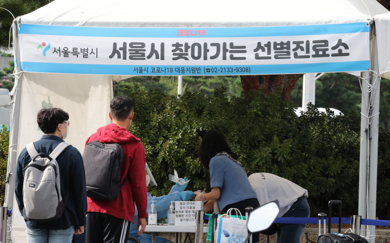 11일 오후 서울시 강서구 김포공항에 마련된 코로나19 임시선별진료소에서 여행을 다녀온 관광객들이 코로나 검사를 받기 위해 줄을 서 있다. [연합]