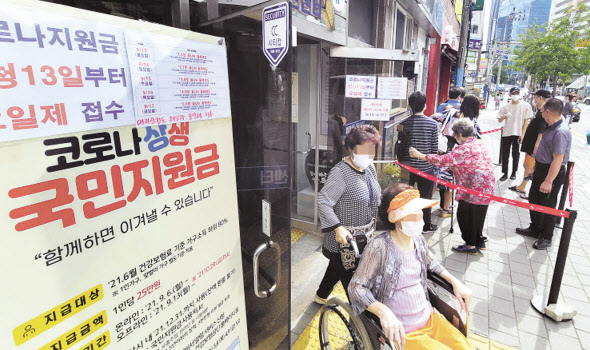 코로나19 상생 국민지원금 오프라인 신청 절차가 시작된 13일 부산 부산진구 범천1동 주민센터에서 시민들이 지원금을 신청하기 위해 줄을 서고 있다. [연합]
