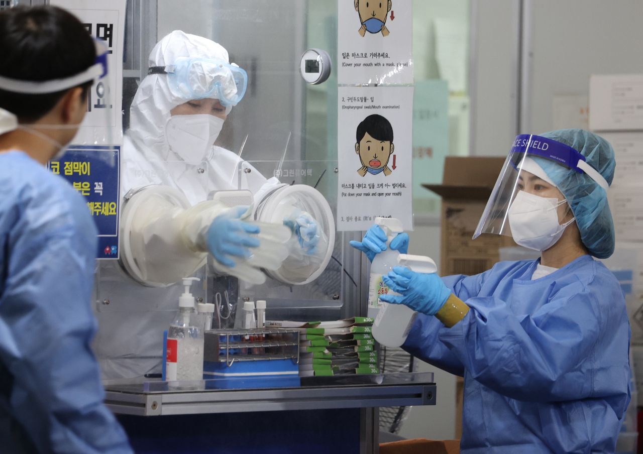 To ease bed shortages, Korea is expanding at-home care for COVID-19 patients who are mildly sick. By Tuesday, more than 3,000 patients nationwide were isolating at home, instead of at medical facilities. This photo taken Oct. 7 shows health care workers at a COVID-19 testing center in Songpa, southern Seoul. (Yonhap)