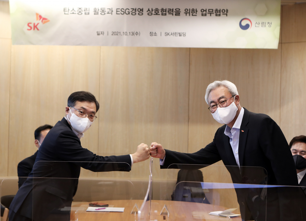 김준 SK수펙스추구협의회 환경사업위원회 위원장(오른쪽)과 최병암 산림청장이 13일 서울 종로구 SK서린빌딩에서 ‘탄소중립 활동과 ESG경영 상호협력을 위한 업무협약’을 체결한 뒤 주먹인사를 하고 있다. [SK 제공]
