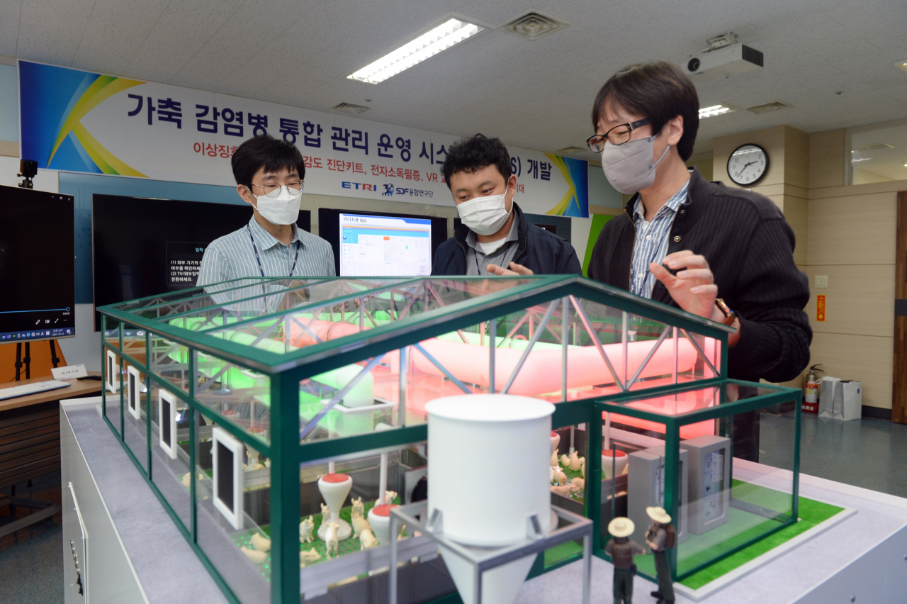 ETRI 연구진이 스마트 축사 모형 앞에서 가축 전염병 통합 관리를 위한 기술 적용을 논의하고 있다.[ETRI 제공]