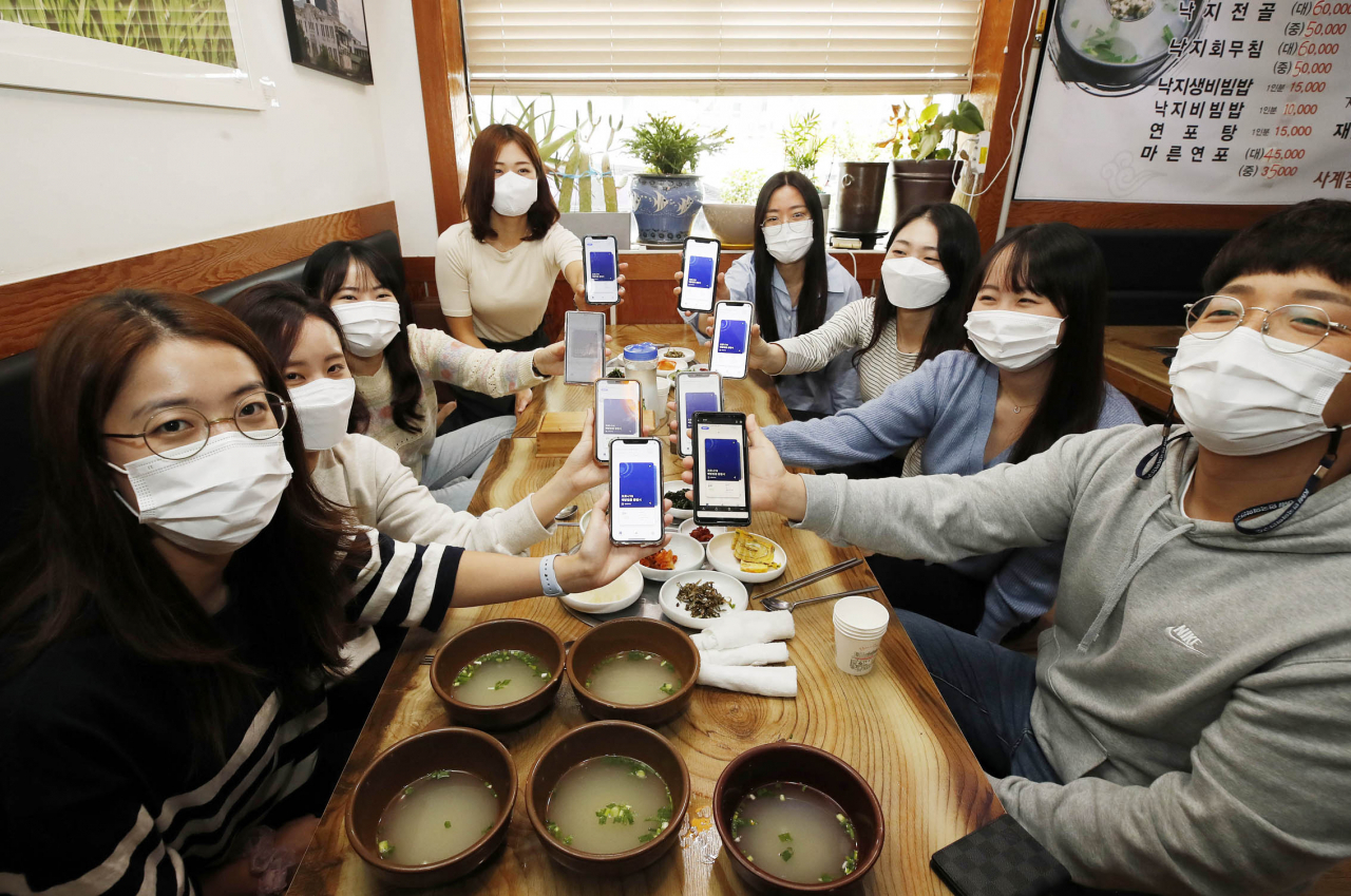 지난 15일 낮 광주 북구 한 식당에서 북구보건소 신종 코로나바이러스 감염증(코로나19) 역학조사 TF팀 직원들이 백신 예방접종 증명서를 보여 주며 식사를 하고 있다. 중앙대책본부에 따르면 18일부터 거리두기 단계는 현재와 같이 2주간 유지되지만 사적 모임 가능 인원은 수도권 최대 8명, 비수도권 최대 10명으로 완화된다. 연합뉴스