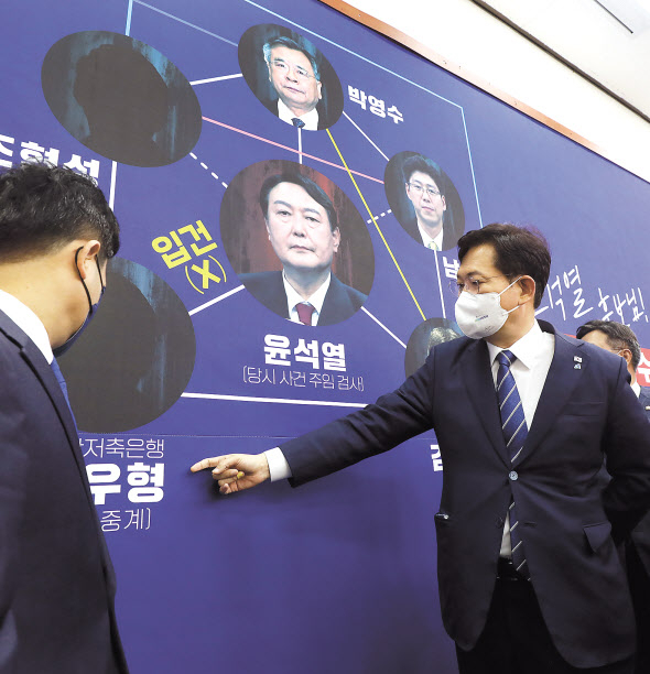송영길 더불어민주당 대표와 최고위원들이 18일 오전 국회에서 열린 최고위원회의에 앞서 대장동 개발 의혹 관련, 부산저축은행 수사를 지적하는 내용이 담긴 배경판을 바라보며 대화를 나누고 있다. 이상섭 기자