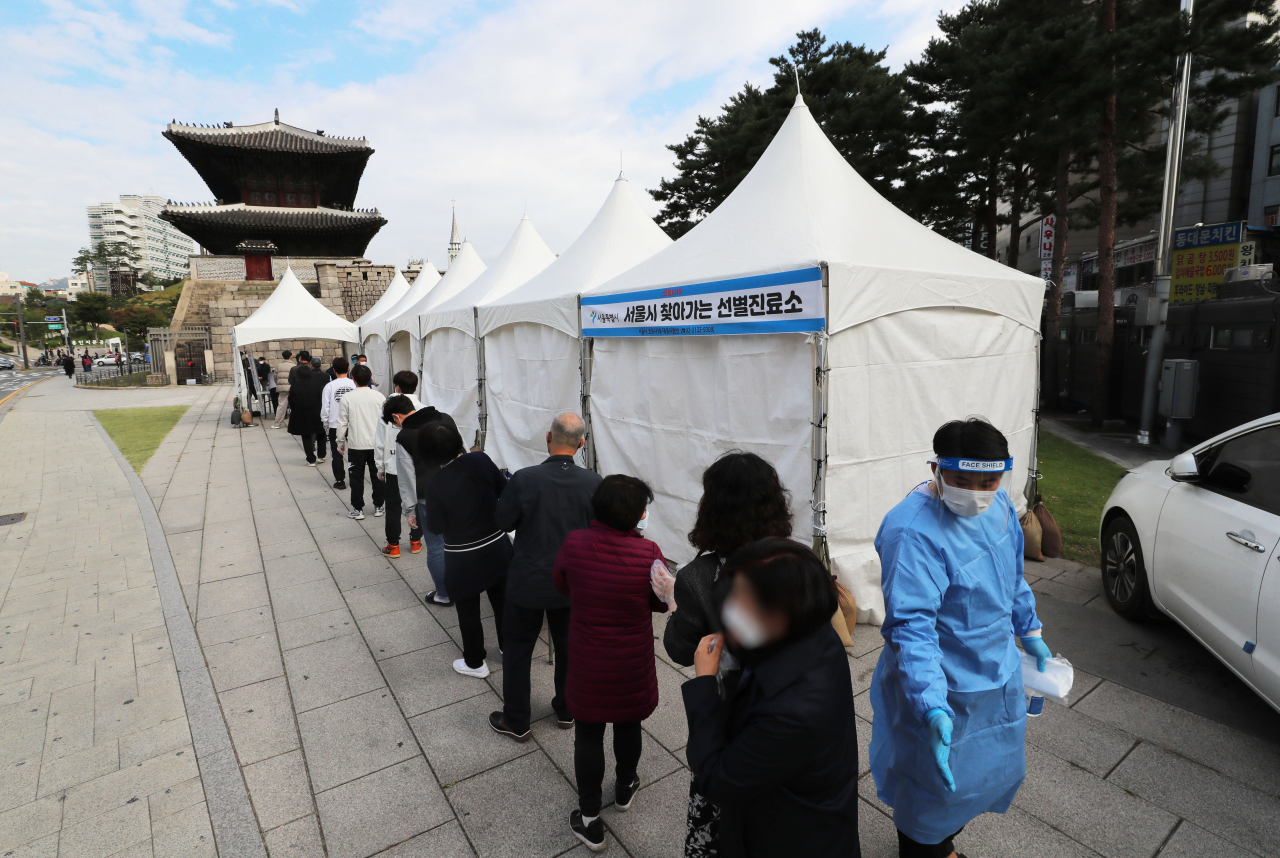 18일 오전 서울 종로구 흥인지문 옆에 설치된 찾아가는 선별검사소에서 코로나19 집단감염이 발생한 동대문 인근 시장 종사자들이 검사를 받기 위해 대기하고 있다. [연합]