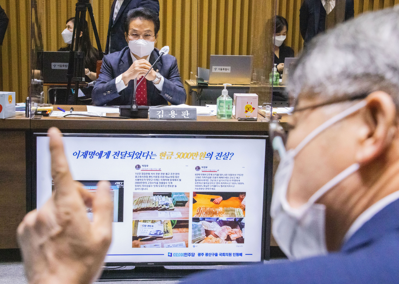 국민의힘 김용판 의원이 19일 오전 서울시청에서 열린 행정안전위원회 국정감사에서 논란이 되고 있는 '김용판 의원의 경기도 국정감사 돈다발 사진자료'를 제시하는 더불어민주당 민형배 의원을 보고 있다. 연합뉴스