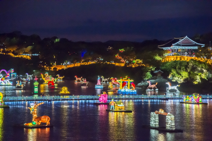 Visitors admiring illuminated lantern displays and fireworks reflected in the Namgang River during the Jinju Namgang Yudeung Festival at night