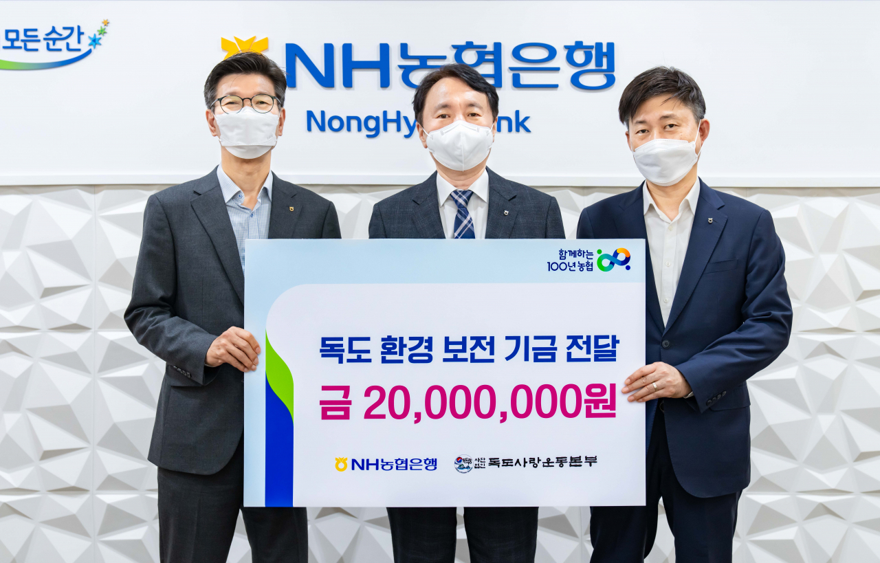농협은행 권준학 은행장(사진 가운데)과 이상래 디지털금융부문 부행장(왼쪽), 고명환 디지털마케팅부장(오른쪽)이 '디지털 독도 걷기대회'를 통해 조성된 공익기금 2천만원을 (사)독도사랑운동본부에 전달하기 위해 기념 촬영을 하고 있다.