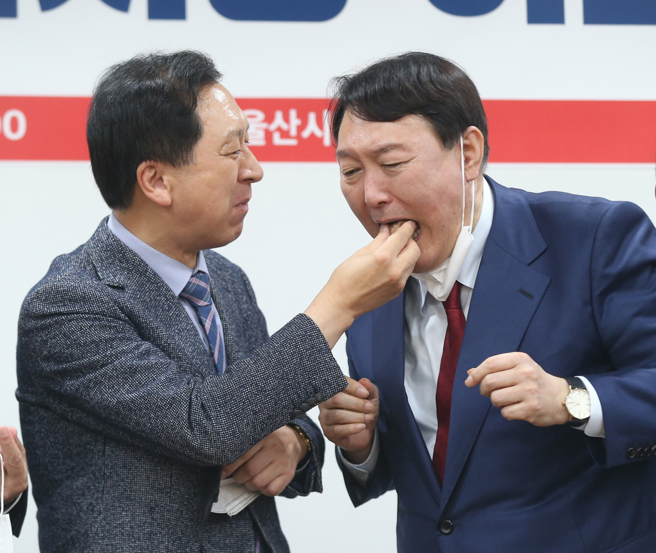 국민의힘 대권주자인 윤석열 전 검찰총장은 24일 “원래 선거라는 건 시쳇말로 패밀리 비즈니스라고 하지 않나”고 말했다. 윤 전 총장이 전날 울산시당 이전 개소식에 참석해 김기현 원내대표가 건네주는 떡을 받아먹고 있다. [연합]