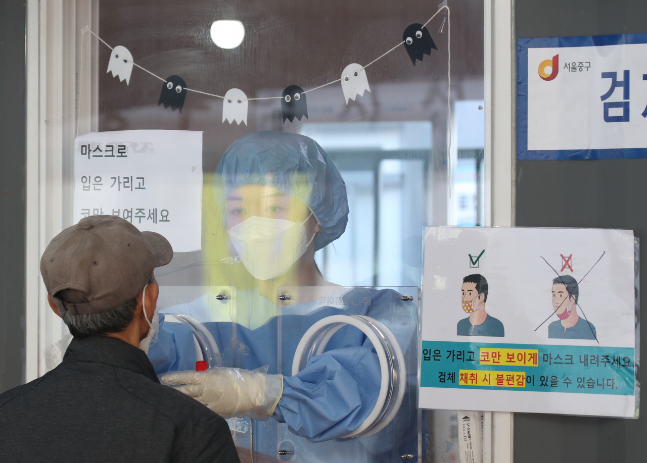 24일 오전 서울 중구 서울역 코로나19 임시 선별검사소에서 의료진이 시민의 검체를 채취하고 있다. 연합뉴스