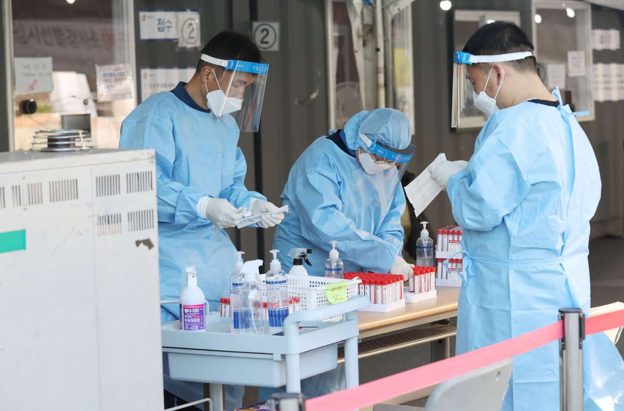 25일 서울역 광장에 마련된 신종 코로나바이러스 감염증(코로나19) 임시 선별검사소에서 의료진들이 검체를 정리하고 있다. [연합]