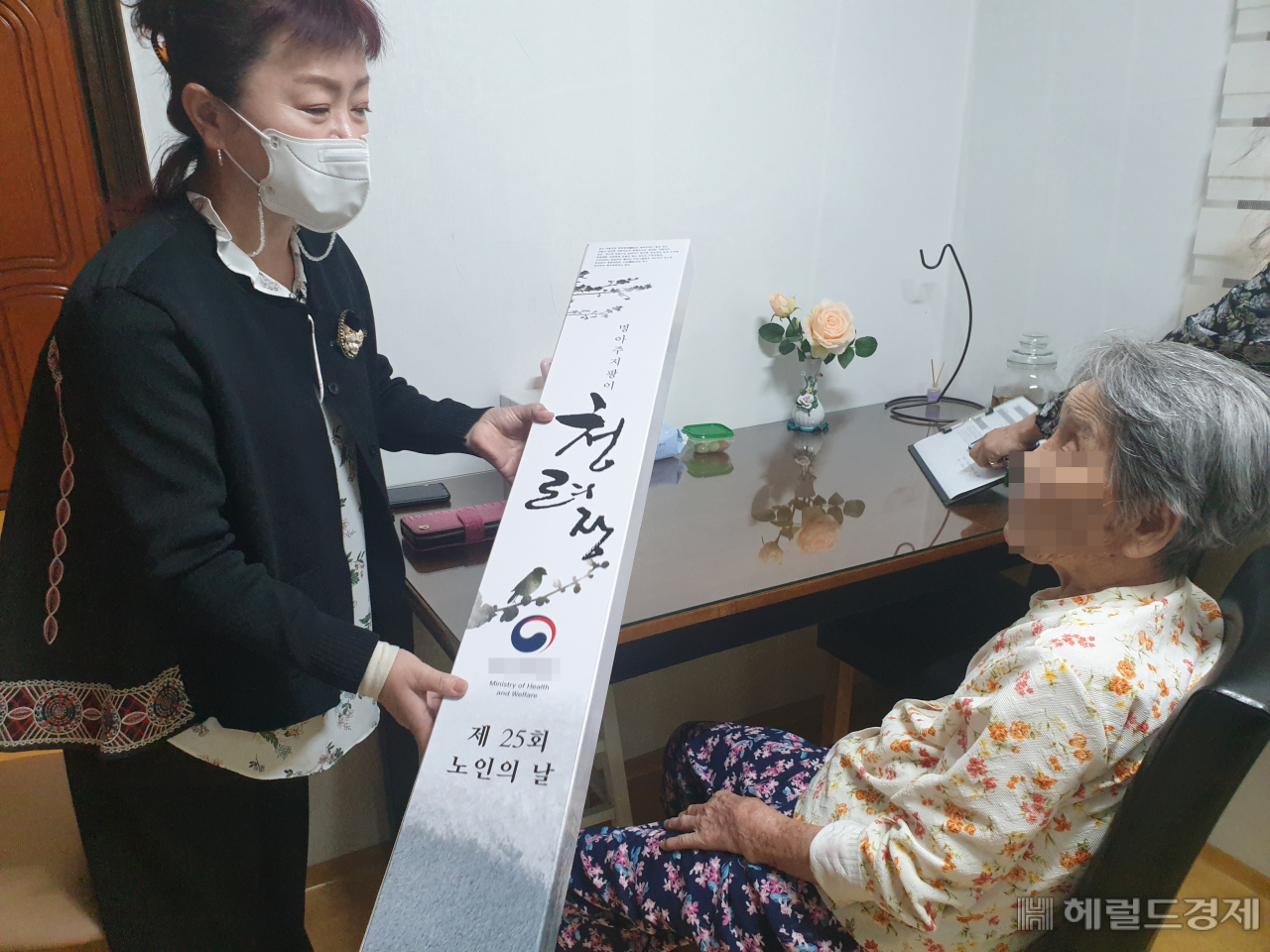 강북구 직원이 100세를 맞은 노인을 찾아가 장수 지팡이를 전달하고 있다. [강북구 제공]