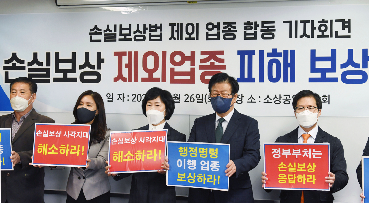 이달 26일 서울 영등포구 여의도 소상공인연합회에서 열린 손실보상법 제외 업종 피해보상 촉구 합동 기자회견에서 참석자들이 손 팻말을 들고 구호를 외치고 있다. [연합]