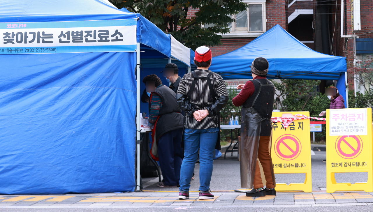 30일 오후 서울 구로시설관리공단 주차장에 마련된 코로나19 서울시 찾아가는 선별진료소를 찾은 인근 남구로시장 상인들이 검사를 받기 위해 차례를 기다리고 있다. [연합]