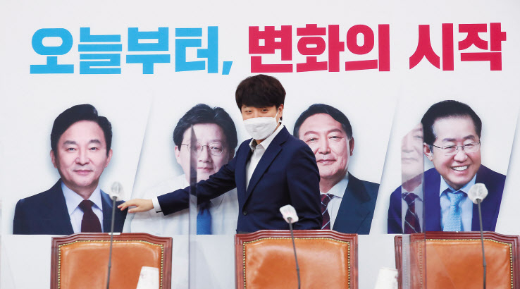 이준석 국민의힘 대표가 1일 국회에서 열린 최고위원회의에 참석하며 배경판에 나온 대선 경선 후보자들의 사진을 살펴보고 있다. 국민의힘은 이날부터 대선후보 선출을 위한 전당대회 투표에 들어갔다. 이상섭 기자