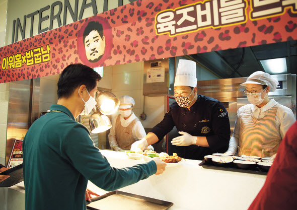 지난 20일 아워홈이 운영하는 여의도 소재 구내식당에서 열린 ‘아워홈 플렉스 테이블’ 이벤트에서 유튜버 ‘밥굽남’이 일일 조리사로 변신해 고객에게 돈마호크카츠 메뉴를 배식하고 있다. [아워홈 제공]