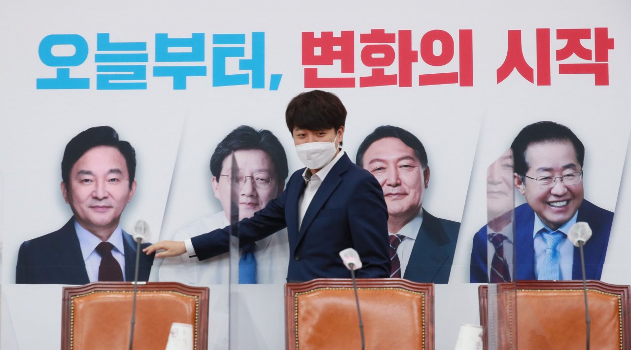 국민의힘 이준석 대표가 1일 서울 여의도 국회에서 열린 최고위원회의에 참석하며 배경판에 나온 대선 경선 후보자들의 사진을 살펴보고 있다. [연합]