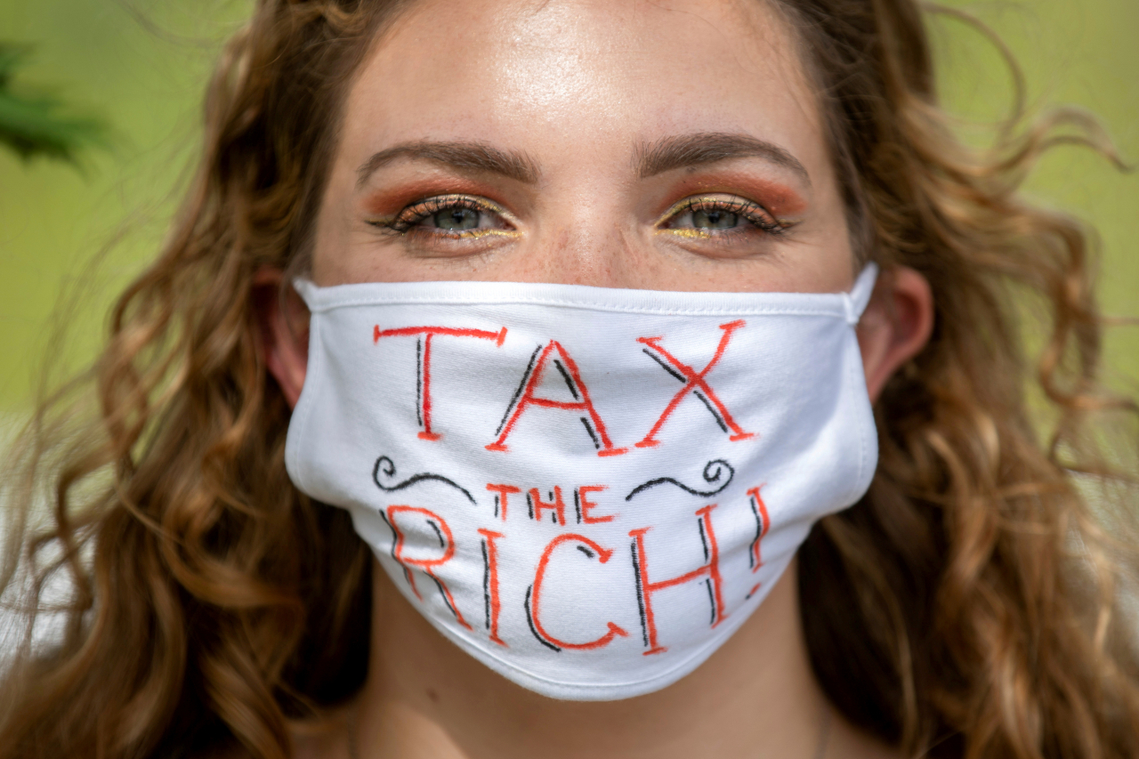 캐나다 온타리오주(州)에서 한 여성이 지난 9월 “부자들에게 세금을(Tax the Rich)”이란 문구가 적힌 마스크를 쓰고 시위를 벌이고 있다. [로이터]