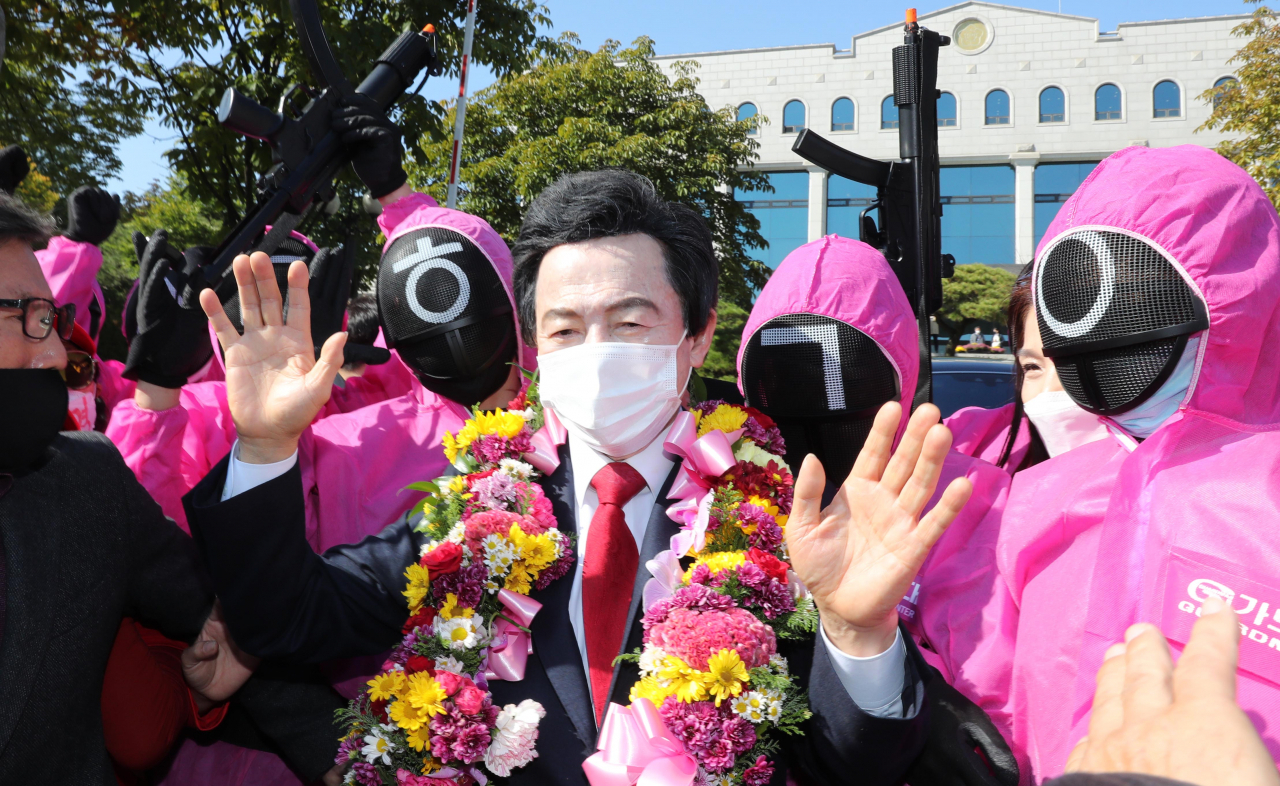 허경영 국가혁명당 명예대표가 지난달 18일 과천 중앙선관위에서 제20대 대통령선거 예비후보자 등록을 마치고 '오징어 게임' 복장을 한 지지자들에 둘러싸여 환호에 답하고 있다. [연합]