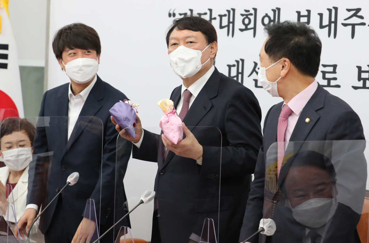 국민의힘 윤석열 대선후보(가운데)가 8일 오전 서울 여의도 국회에서 열린 최고위원회의에서 이준석 대표(왼쪽)로부터 비단주머니를 받고 발언하고 있다. [연합]