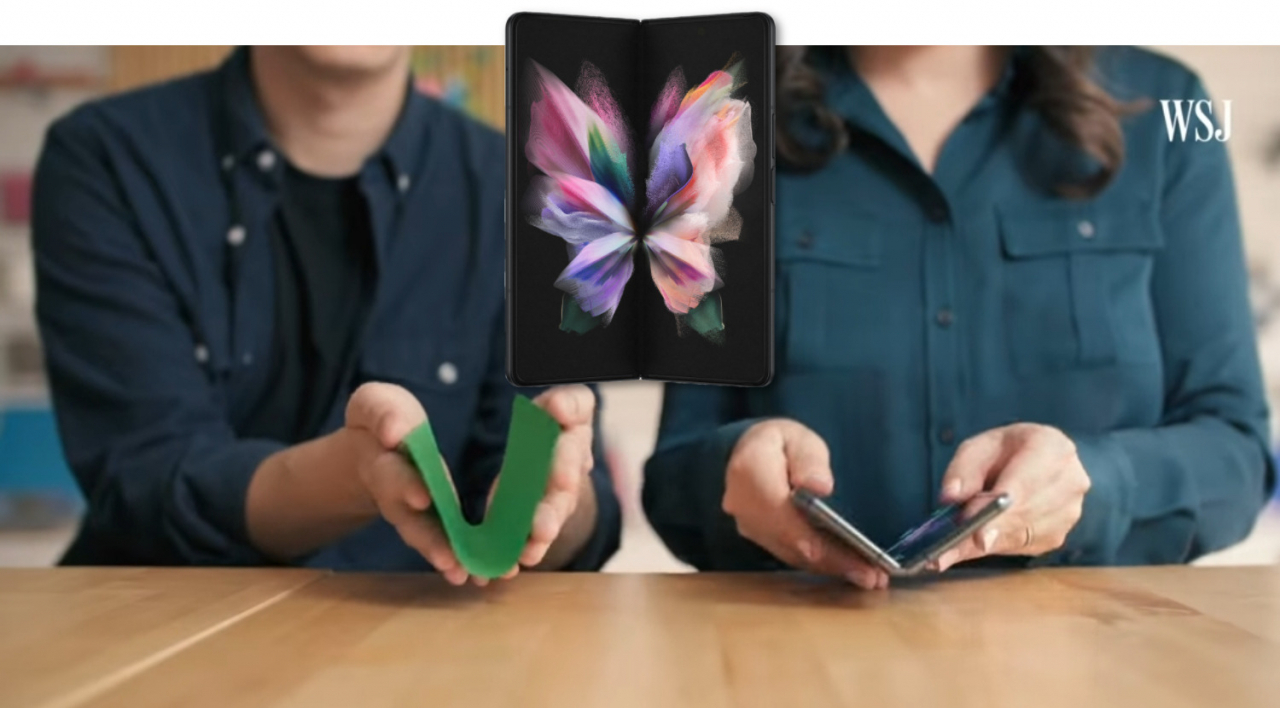 2019년 4월, 월스트리저널은 '갤럭시폴드 5G'의 내구성을 비판하는 영상을 게시했다. 사진은 조아나 스턴 테크 칼럼니스트가 "차라리 종이 비행기를 접으라"며 색종이와 '갤럭시폴드 5G'를 접는 모습. 가운데 제품은 올해 출시된 '갤럭시Z폴드3'. [WSJ 유튜브 캡처]