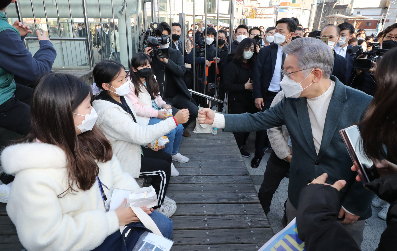 더불어민주당 이재명 대선후보가 13일 경남 창원시 마산합포구 마산어시장으로 이동하던 중 어린이와 인사하고 있다. 연합뉴스